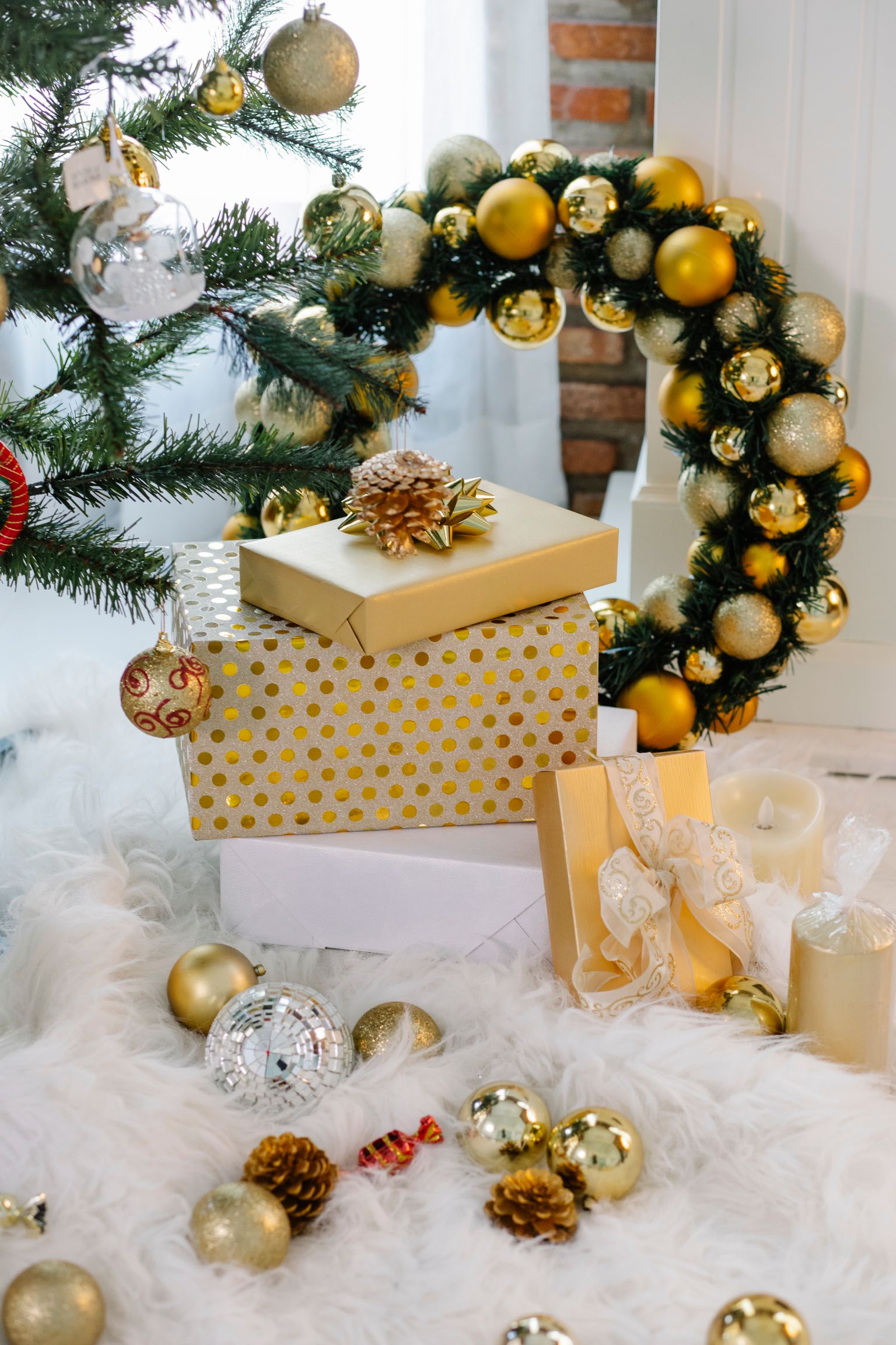 Wrapped holiday gifts arranged beside a tree in a compact apartment